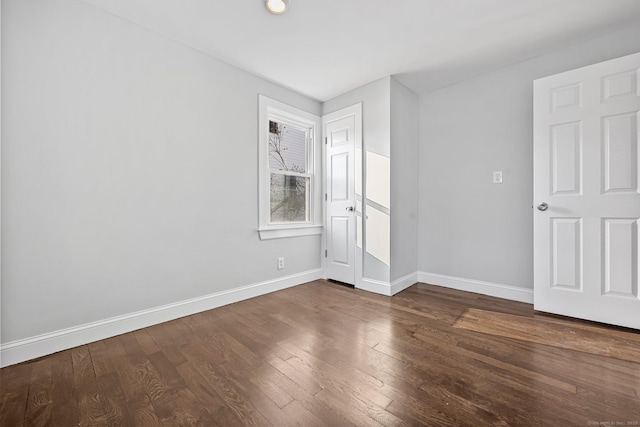 unfurnished room featuring baseboards and dark wood-style flooring