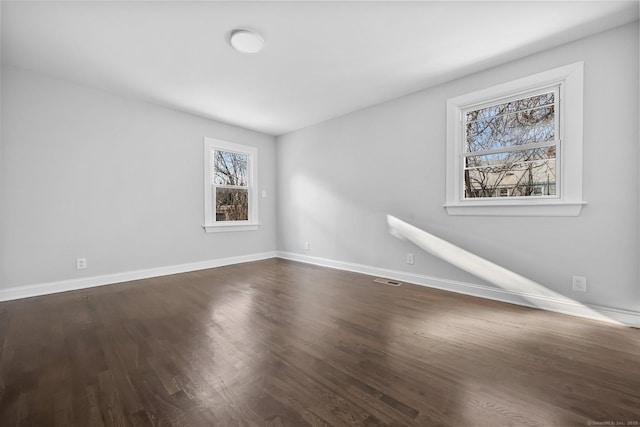 unfurnished room with baseboards and dark wood-style flooring