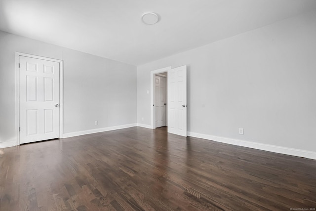 unfurnished room with dark wood finished floors and baseboards