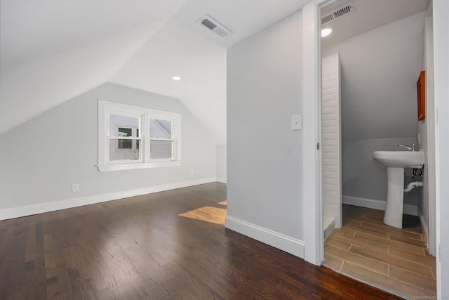 additional living space with a sink, wood finished floors, visible vents, and baseboards