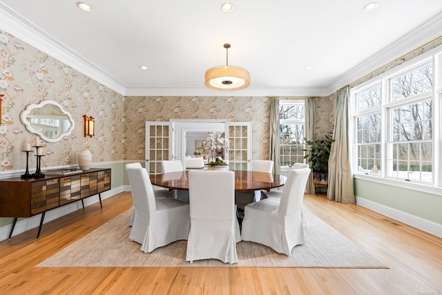 dining room with crown molding, light wood-style flooring, and wallpapered walls