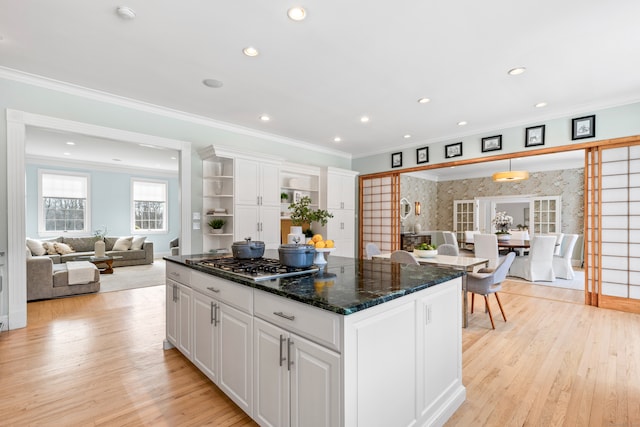 kitchen featuring white cabinets, a kitchen island, crown molding, light wood-style floors, and stainless steel gas cooktop