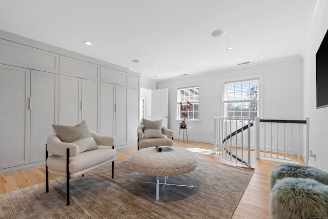 living area featuring crown molding, light wood finished floors, and an upstairs landing