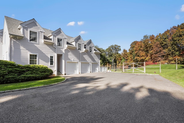 view of front of home featuring aphalt driveway, a front yard, and a shingled roof