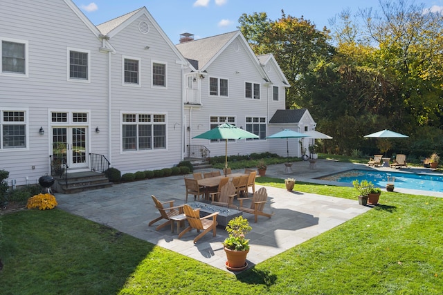 rear view of property with an outdoor pool, french doors, a patio, a chimney, and a yard