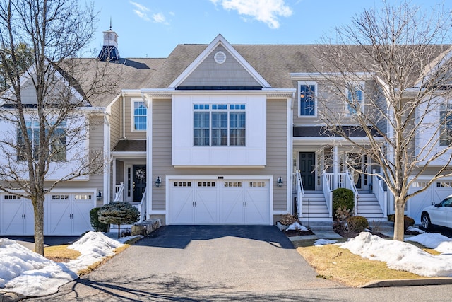 view of front of home with a garage, roof with shingles, and driveway