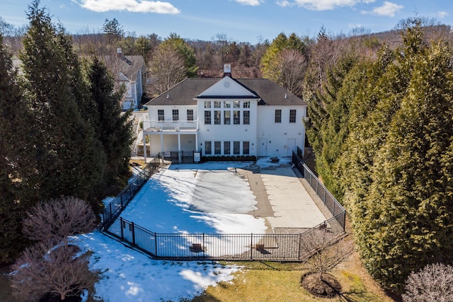 back of house with a balcony, a patio area, a chimney, and fence