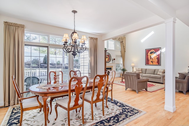 dining space with light wood-style floors, plenty of natural light, a fireplace, and an inviting chandelier