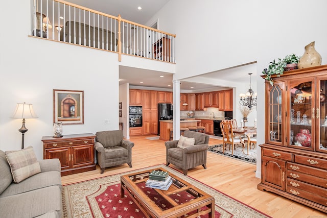 living area featuring a chandelier, recessed lighting, decorative columns, and light wood-style floors