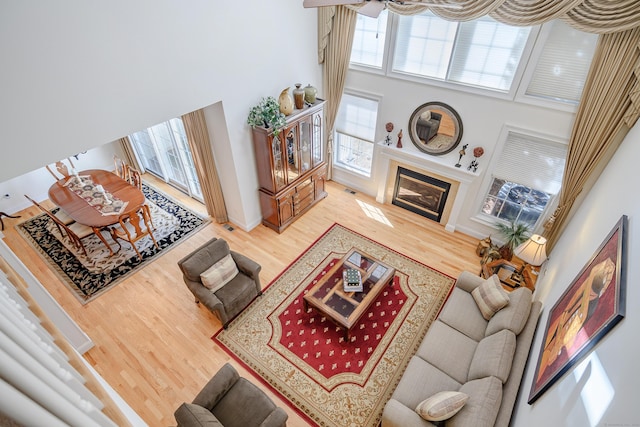 living room with a fireplace with flush hearth, a high ceiling, baseboards, and wood finished floors