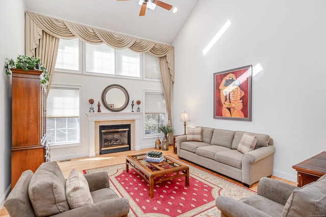 living area featuring plenty of natural light, high vaulted ceiling, wood finished floors, and a glass covered fireplace