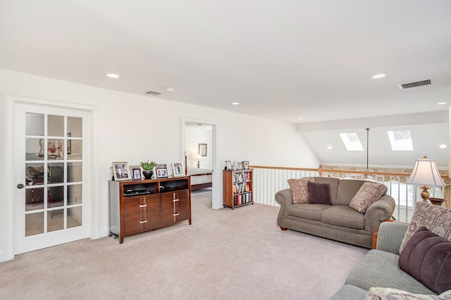 living room with lofted ceiling with skylight, recessed lighting, visible vents, and light colored carpet