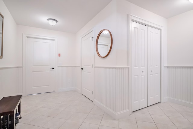 corridor featuring light tile patterned floors and wainscoting