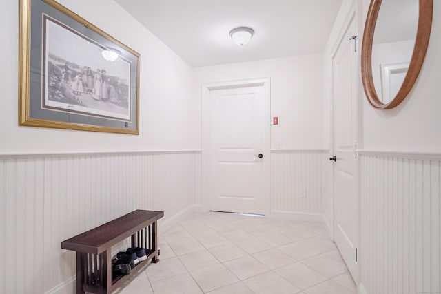 doorway with a wainscoted wall and light tile patterned floors