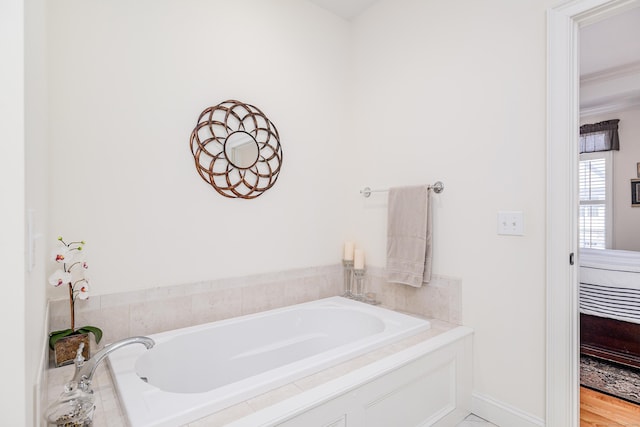 ensuite bathroom featuring baseboards, crown molding, a bath, and ensuite bathroom