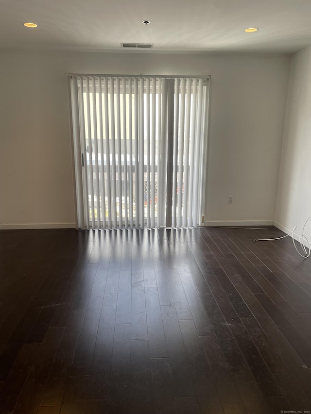 empty room with recessed lighting, dark wood-style flooring, visible vents, and baseboards