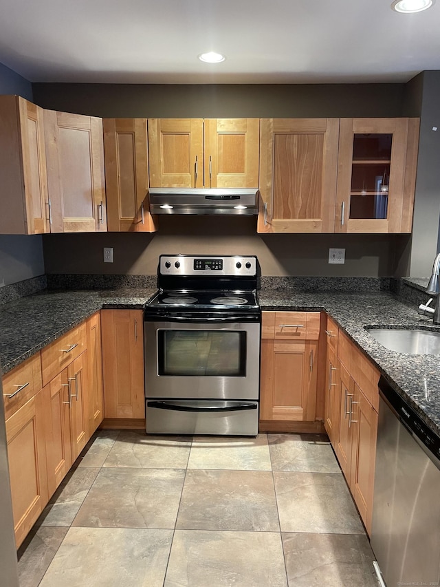 kitchen with recessed lighting, appliances with stainless steel finishes, a sink, dark stone countertops, and under cabinet range hood