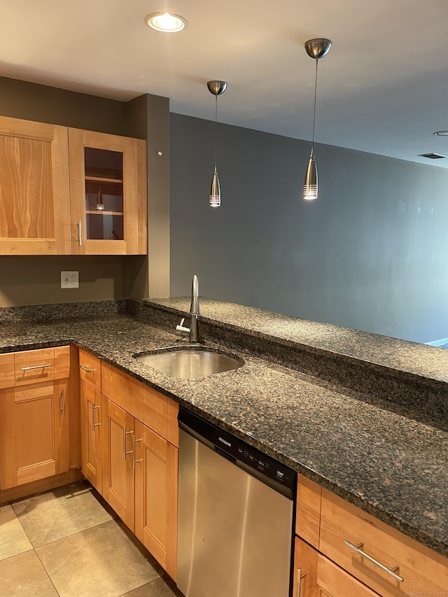 kitchen featuring dark stone counters, stainless steel dishwasher, and a sink