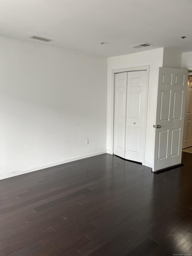 spare room featuring baseboards, visible vents, and dark wood finished floors