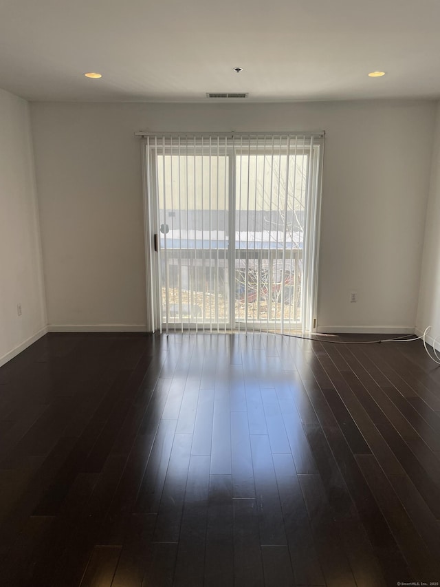 empty room with dark wood-style flooring, recessed lighting, visible vents, and baseboards