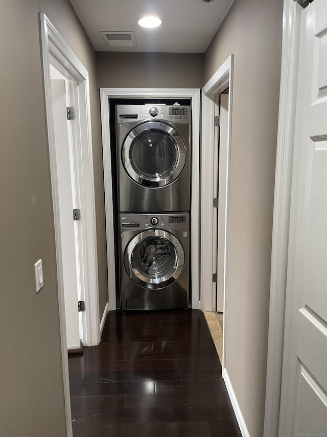 laundry area with laundry area, wood finished floors, visible vents, baseboards, and stacked washer and clothes dryer