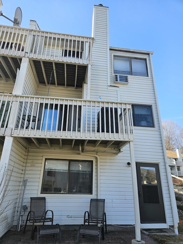 back of property with a balcony and a chimney