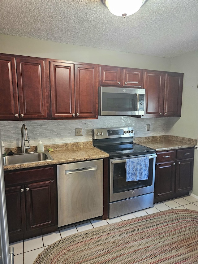 kitchen with light tile patterned floors, backsplash, appliances with stainless steel finishes, and a sink