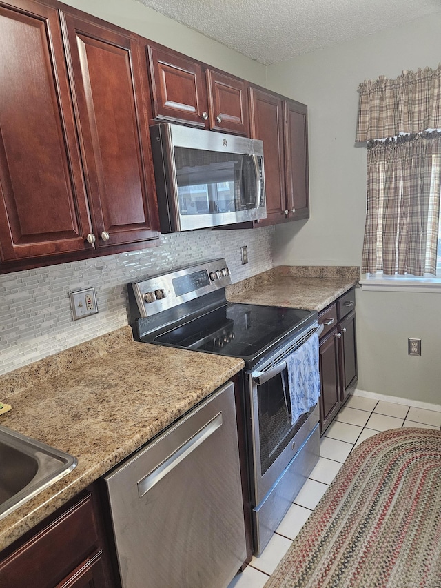 kitchen with stainless steel appliances, backsplash, light tile patterned flooring, and a textured ceiling