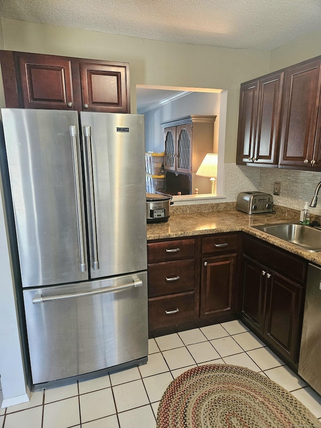 kitchen featuring dishwashing machine, freestanding refrigerator, a sink, a textured ceiling, and backsplash