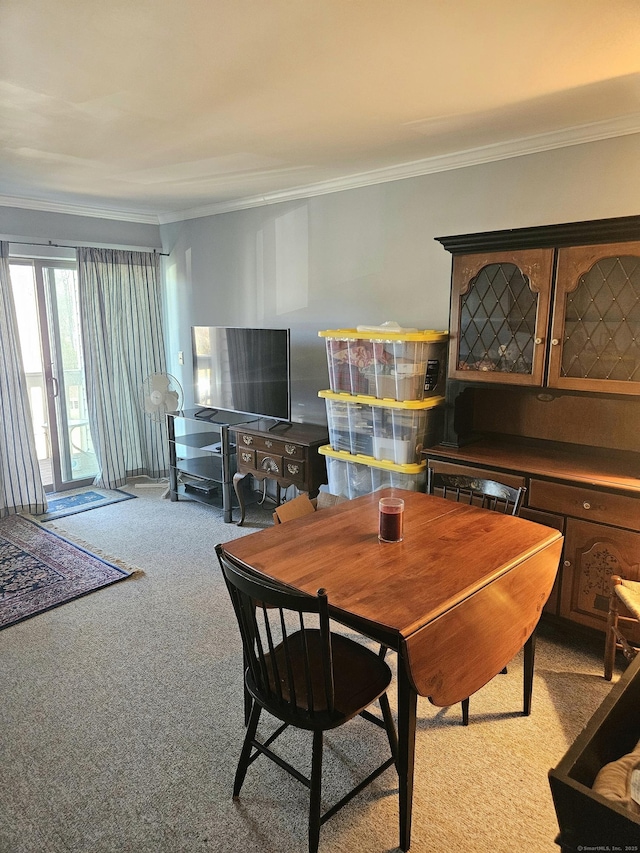 carpeted dining room featuring ornamental molding