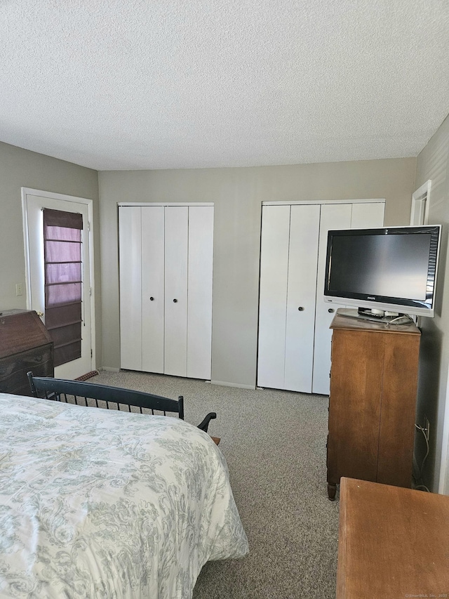 bedroom with carpet, multiple closets, and a textured ceiling