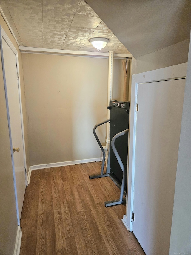 workout area with baseboards and wood finished floors