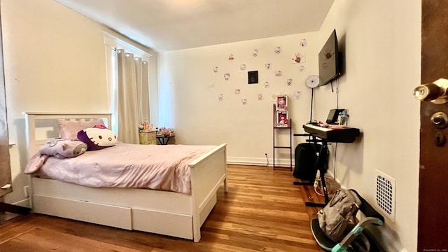 bedroom with visible vents, baseboards, and wood finished floors