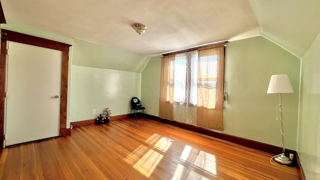 additional living space featuring baseboards, vaulted ceiling, and hardwood / wood-style floors