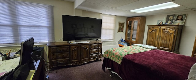 bedroom featuring a drop ceiling and dark carpet