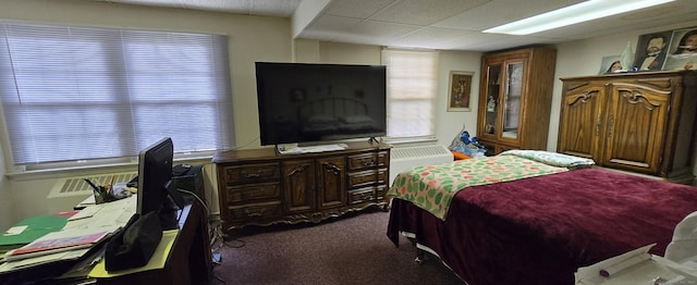 bedroom featuring a paneled ceiling and dark carpet