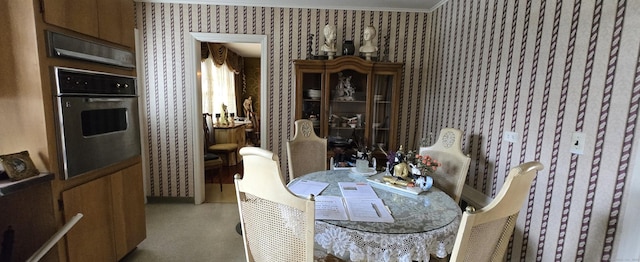 dining space with finished concrete flooring, crown molding, and wallpapered walls