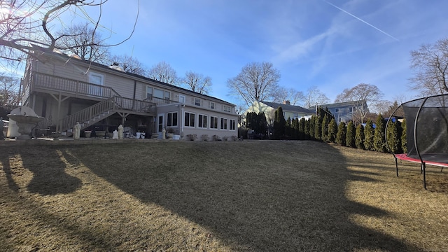 view of yard featuring stairway, a sunroom, a trampoline, and a deck