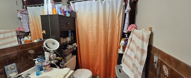 full bath featuring a shower with curtain, tile walls, and toilet