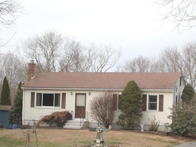 single story home featuring entry steps, a chimney, and a front yard