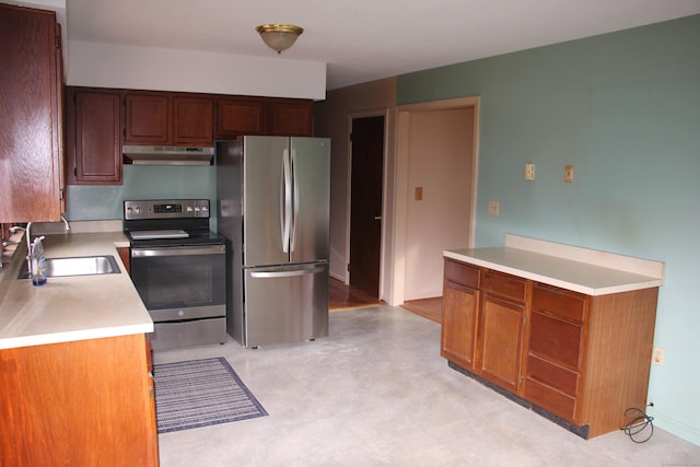 kitchen with under cabinet range hood, appliances with stainless steel finishes, light countertops, and a sink