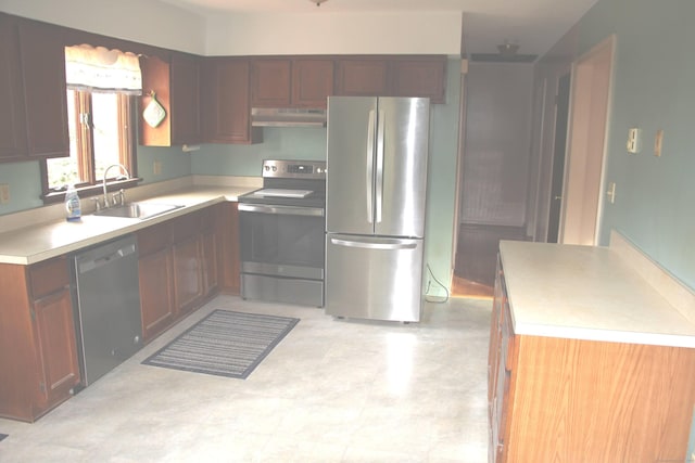 kitchen featuring stainless steel appliances, a sink, light countertops, and under cabinet range hood