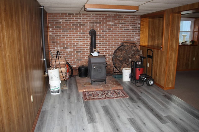 details featuring a paneled ceiling, a wood stove, wood finished floors, and wood walls