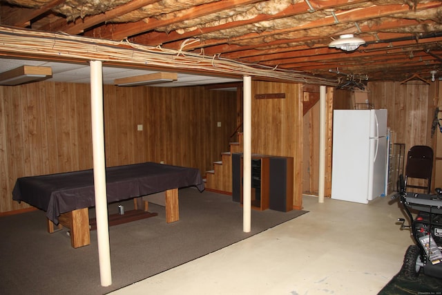 unfinished below grade area with stairs, pool table, freestanding refrigerator, and wooden walls