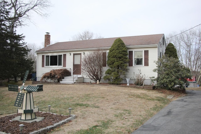 single story home with roof with shingles, a chimney, and a front yard