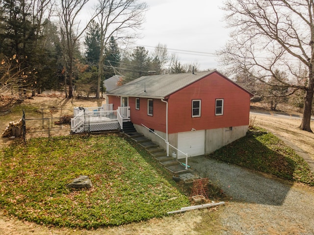 view of property exterior with driveway, a deck, an attached garage, and a lawn