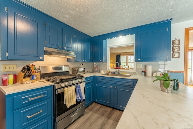 kitchen featuring a toaster, dark wood-type flooring, under cabinet range hood, a sink, and gas stove