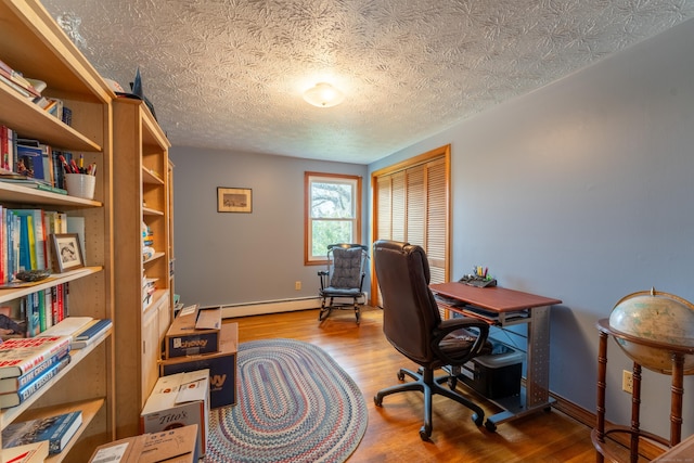 office space featuring a baseboard heating unit, a textured ceiling, baseboards, and wood finished floors