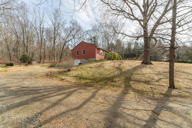 view of side of home with dirt driveway, crawl space, and a chimney