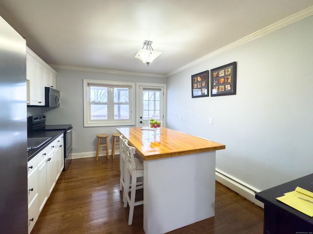 kitchen featuring butcher block countertops, appliances with stainless steel finishes, dark wood-type flooring, baseboard heating, and white cabinetry